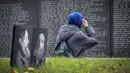 Seorang perempuan mengunjungi tugu peringatan bagi para korban represi politik di Butovo, di luar Moskow, pada Kamis 30 Oktober 2025, menandai hari peringatan. Pada tahun 1995, Gereja Ortodoks Rusia mengambil alih kepemilikan Butovo dan mendirikan kompleks peringatan, termasuk tembok peringatan yang memuat nama-nama korban yang teridentifikasi. (Nikita BORISSOV/AFP)