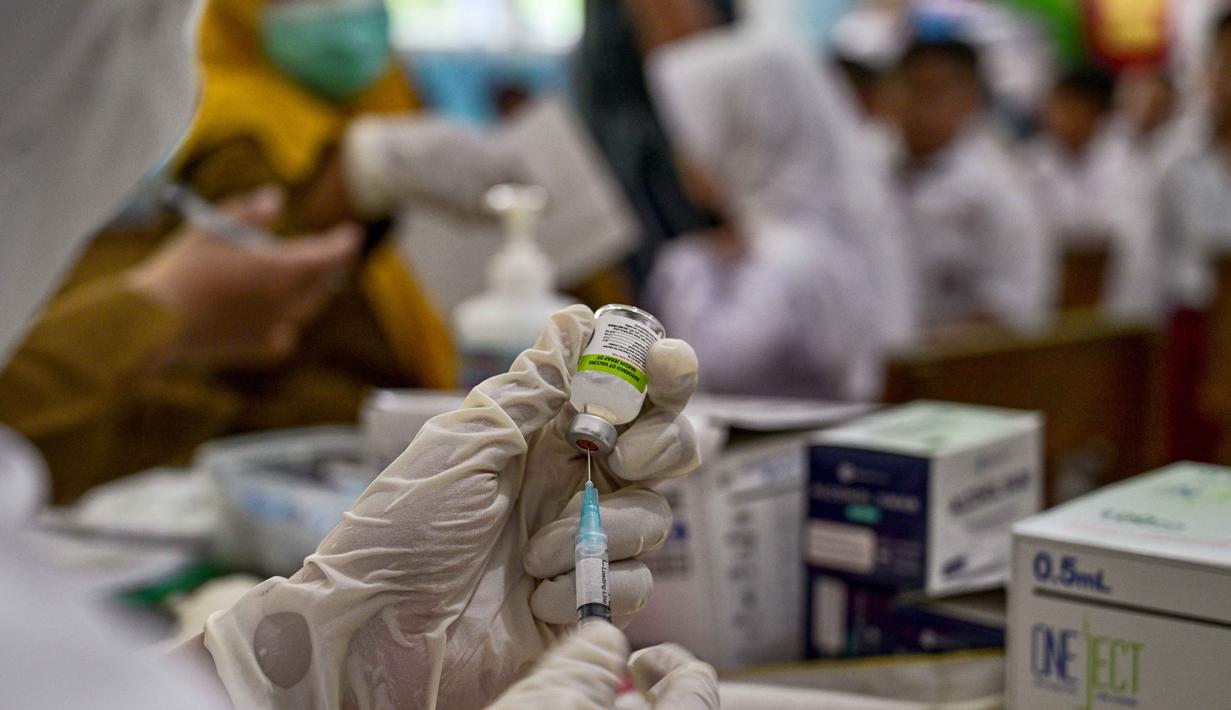 Seorang tenaga kesehatan sedang mempersiapkan vaksin difteri untuk murid-murid di sebuah sekolah dasar di Surabaya pada Selasa 4 November 2025. Sementara tahap kedua pada November mencakup vaksin Difteri-Tetanus (DT) untuk kelas 1 dan Tetanus-Difteri (Td) bagi kelas 2, 5, dan 9. (Juni KRISWANTO/AFP)