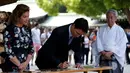 PM Kanada Justin Trudeau dan sang istri dikawal oleh seorang imam Shinto menulis pesan pada 'ema' atau sebuah harapan yang mereka tulis di sebuah kayu di Kuil Meiji di Tokyo, Jepang (24/5).  (REUTERS/Issei Kato)