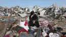 Seorang wanita Palestina yang terpaksa mengungsi duduk bersama barang-barangnya setelah serangan Israel di kamp pengungsi Deir el-Balah, Jalur Gaza tengah, pada 21 Agustus 2025. (Eyad BABA/AFP)