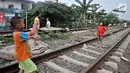 Anak-anak bermain layang-layang di rel kereta api kawasan Jakarta Timur, Kamis (3/1). Rel yang sering dilintasi kereta api tersebut sangat membahayakan diri mereka. (Merdeka.com/Iqbal Nugroho)