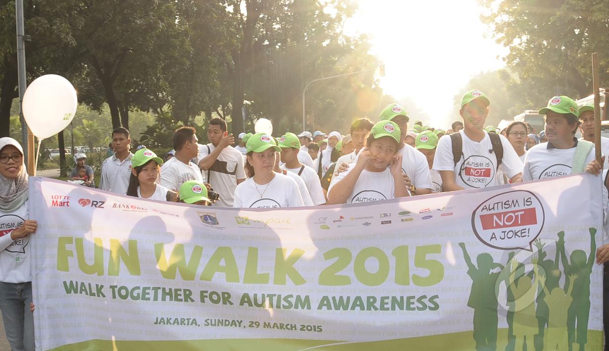 Para peserta fun walk 2015 Autism is not a joke berjalan membawa spanduk di balai kota, Jakarta, Minggu (29/3/2015). acara ini dalam rangka memperingati hari autisme sedunia yang jatuh tanggal 2 april setiap tahunnya. (Liputan6.com/Herman Zakharia)