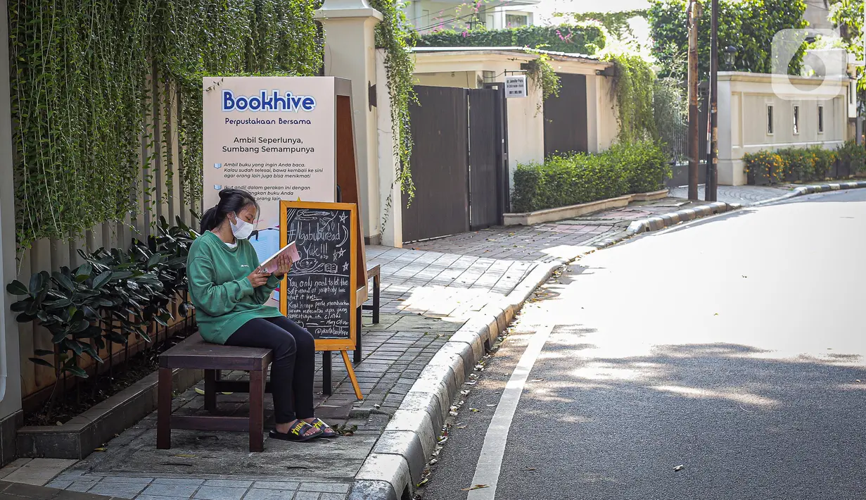 Warga membaca buku dekat perpustakaan bersama Bookhive Jakarta di kawasan Taman Situ Lembang, Jakarta, Selasa (27/4/2021). Warga bisa meminjam dan menyumbang buku pada rak terbuka Bookhive Jakarta. (Liputan6.com/Faizal Fanani)