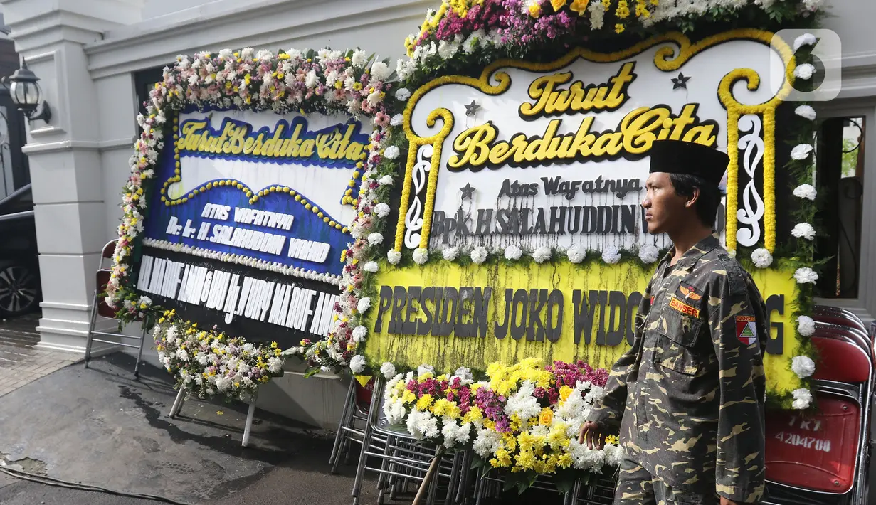Warga berdiri dekat karangan bunga ucapan duka cita atas meninggalnya KH Salahuddin Wahid atau Gus Sholah di kawasan Mampang Prapatan, Jakarta, Senin (3/2/2020). Gus Sholah akan dimakamkan di kompleks pemakaman keluarga di dalam kawasan Pesantren Tebuireng, Jawa Timur. (Liputan6.com/Herman Zakharia)