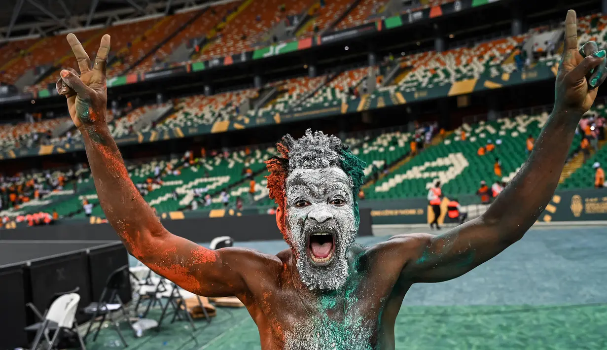 Seorang suporter Pantai Gading melakukan selebrasi saat timnya menjuarai Piala Afrika 2023 setelah mengalahkan Nigeria dengan skor 2-1 pada partai final yang berlangsung di Alassane Ouattara Olympic Stadium, Ebimpe, Abidjan, Pantai Gading, Minggu (11/02/2024) waktu setempat. (AFP/Sia Kambou)