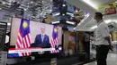 Seorang staf toko elektronik yang mengenakan masker melihat siaran langsung Perdana Menteri Malaysia Muhyiddin Yassin berbicara di sebuah outlet perbelanjaan di Kuala Lumpur, Malaysia, Senin (16/8/2021). Dalam pidatonya, Muhyiddin berkata penangangan COVID-19 di Malaysia gagal. (AP Photo/FL Wong)