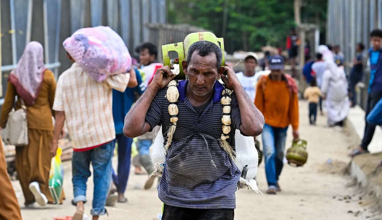 Diharapkan, dengan selesainya pembangunan jembatan bailey, distribusi bantuan logistik untuk warga terdampak bencana hidrometeorologi di Bireuen, Aceh, menjadi lancar. Tampak dalam foto, seorang pria membawa tabung gas menyeberangi sungai di jembatan yang baru dibangun yang menghubungkan Aceh dan Provinsi Sumatera Utara setelah hancur akibat banjir bandang di Sungai Peusangan, Bireuen, Provinsi Aceh, Selasa 9 Desember 2025. (CHAIDEER MAHYUDDIN/AFP)