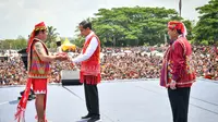 Presiden Jokowi menerima penutup kepala khas Suku Dayak dari Kepala Adat Besar Kutai Barat Manar Dimansyah disaksikan Bupati Kutai Barat FX Yapan.