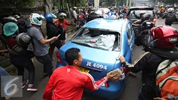 Sejumlah ojek online mengunakan batu merusak taksi di kawasan Senayan, Jakarta, Selasa (22/3). Pascabentrok ojek online melakukan sweeping dan perusakan terhadap taksi serta bajaj yang melintas di kawasan tersebut. (Liputan6.com/Immanuel Antonius)