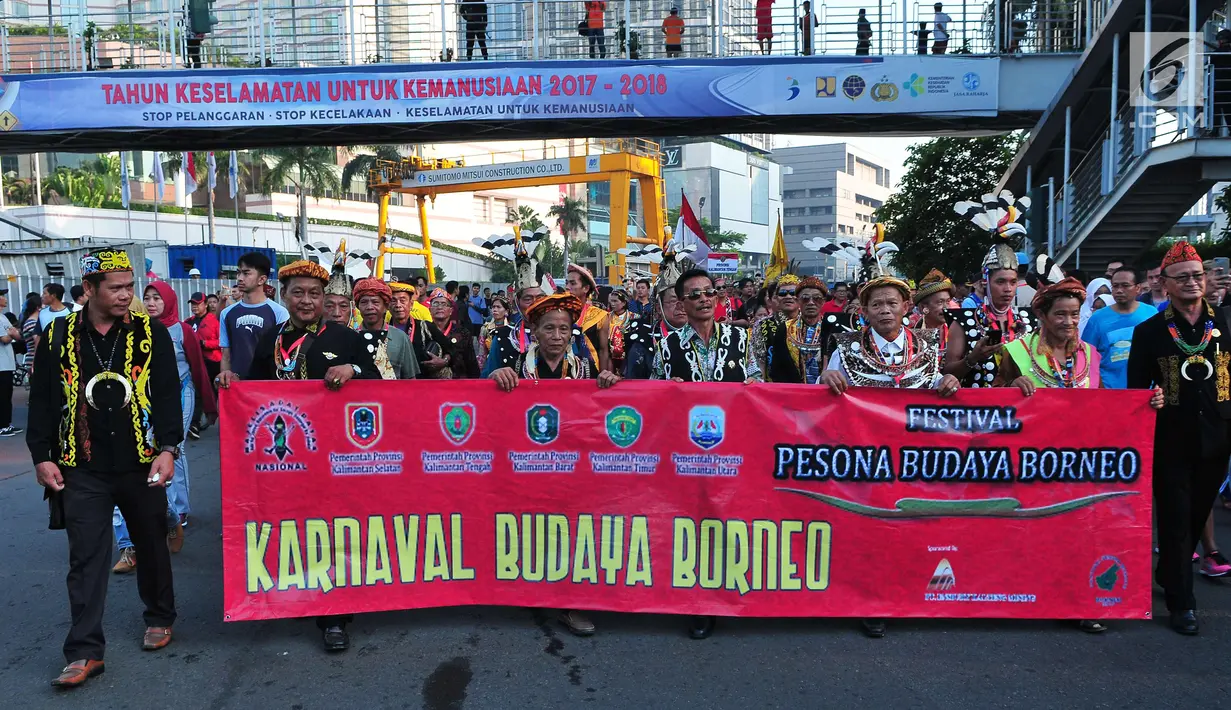 Peserta pawai mengenakan pakaian adat membentangkan spanduk saat festival Budaya Borneo di Car Free Day, Jakarta, Minggu (30/7). (Liputan6.com/Helmi Afandi)