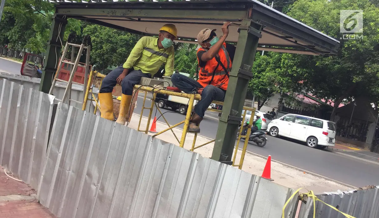 Pekerja menyelesaikan pembuatan halte bus di depan Mesjid Istiqlal, Jakarta, Sabtu (6/1). Pembuatan halte tersebut dilakukan untuk meningkatkan kenyamanan bagi pengguna transportasi umum. (Liputan6.com/Immanuel Antonius)