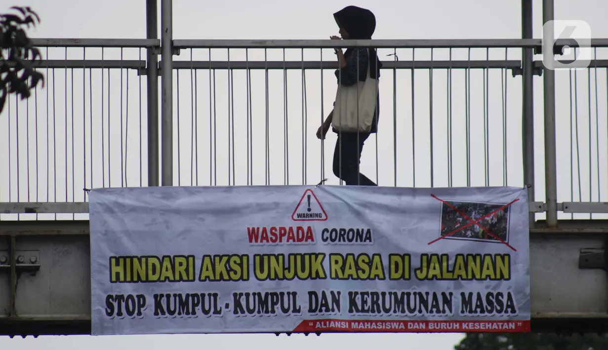 Pejalan kaki melintasi Jembatan Penyeberangan Orang (JPO) di Jalan Raya Lenteng Agung, Jakarta, Selasa (17/3/2020). Sebuah spanduk berisi ajakan menghindari kerumunan dan kumpul-kumpul untuk mencegah penyebaran virus Corona COVID-19 terpasang di JPO teresebut. (Liputan6.com/Helmi Fithriansyah)