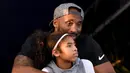Mantan pebasket LA Lakers, Kobe Bryant, bersama putrinya Gianna menyaksikan Kejuaraan Renang Nasional di Woollett Aquatics Center, Jumat (26/7/2018). (AFP/Harry How)