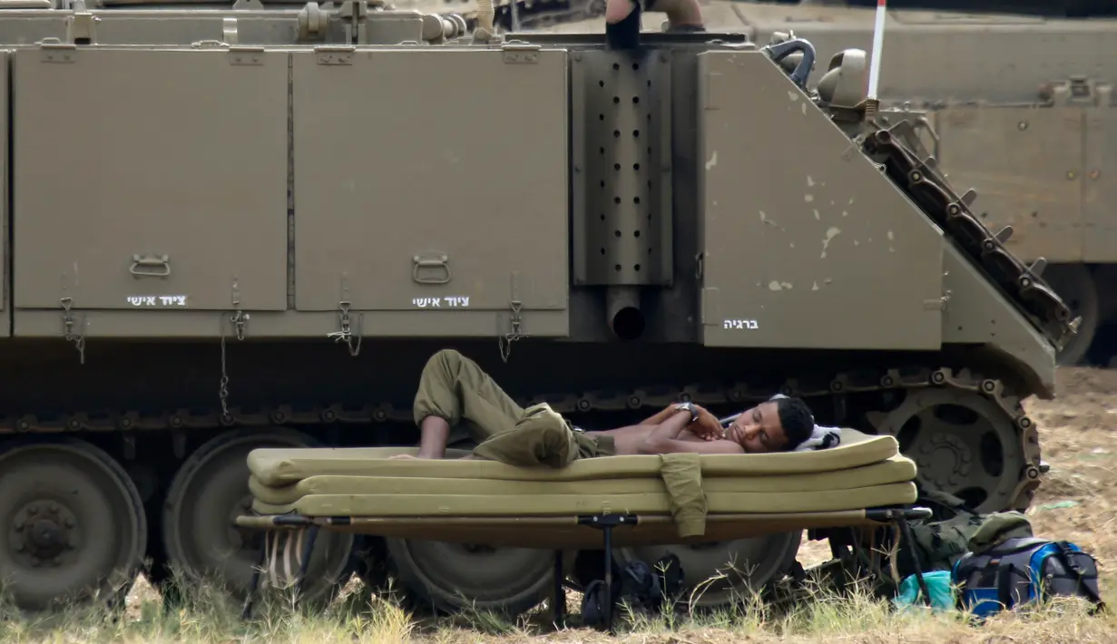 Tentara Israel tidur di samping kendaraan militer di dekat perbatasan Gaza-Israel, Jumat (19/10). Warga Palestina menuntut diakhirinya blokade Israel di Gaza dan hak untuk kembali ke tanah mereka setelah terusir sejak tahun 1948. (AP Photo/Ariel Schalit)