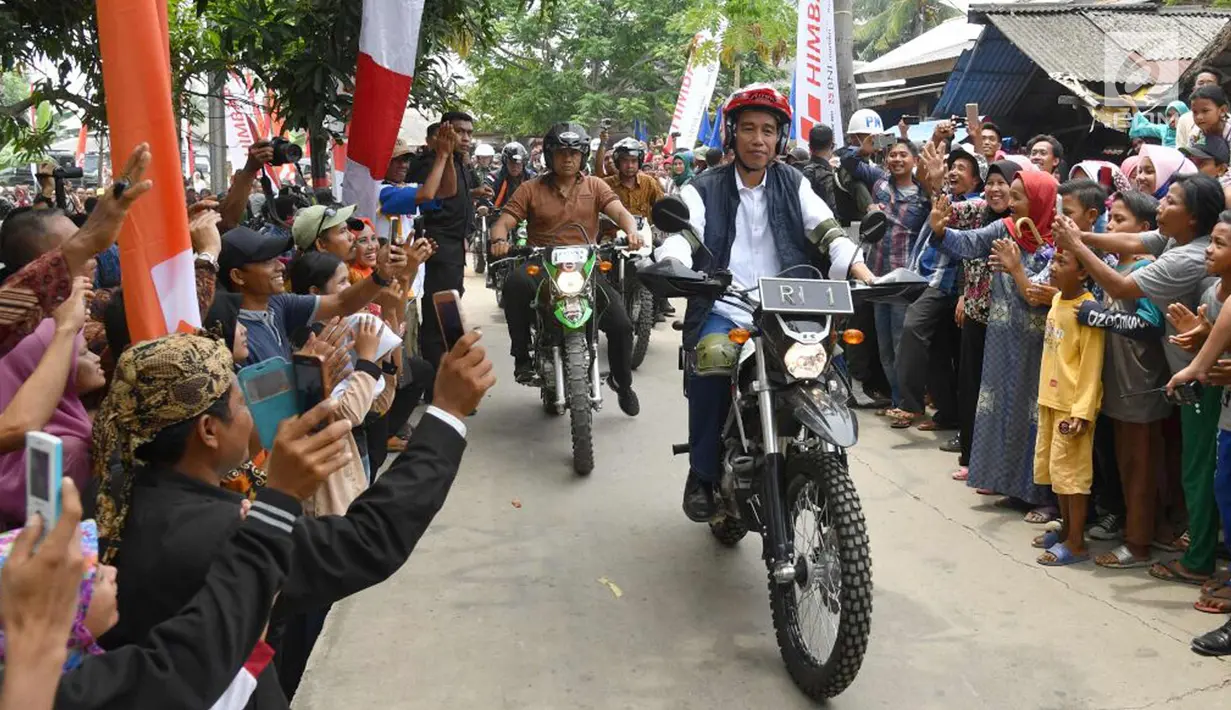 Warga menyambut kedatangan Presiden Joko Widodo saat mengendarai motor trail di Muara Gembong, Bekasi (1/11). Jokowi mengenakan kemeja putih, celana jeans, dengan balutan jaket rompi berwarna hitam. (Liputan6.com/Biro Pers Kepresidenan/Agus Suparto)