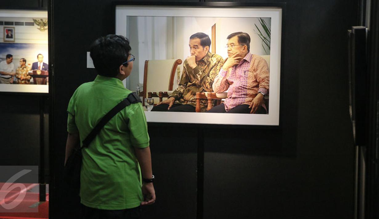 Pengunjung mengamati karya foto yang dipajang pada pameran foto jurnalistik Setahun Kerja Jokowi-JK di Museum Bank Mandiri, Jakarta, Jumat (18/12). Pameran itu mengangkat berbagai kegiatan Kabinet Kerja selama setahun. (Liputan6.com/Faizal Fanani)