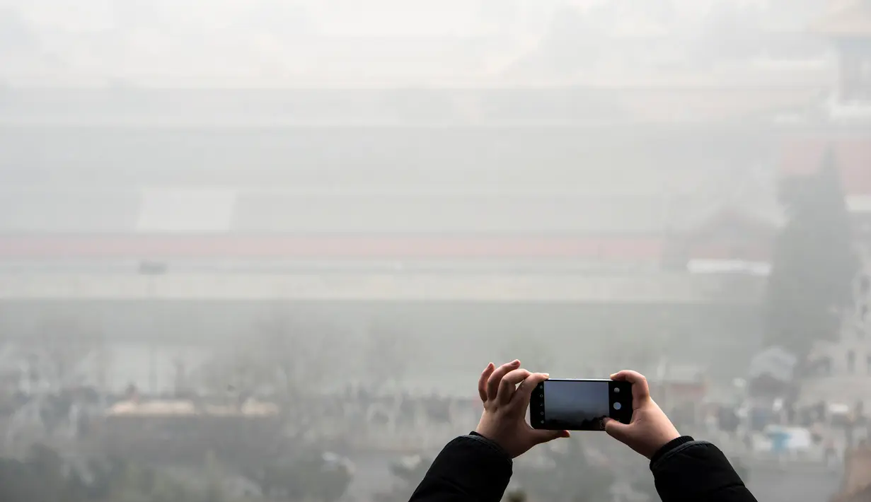 Warga mengabadikan gambar suasana kota Beijing yang diselimuti kabut asap tebal, Cina, 1 Januari 2017. (REUTERS/Stringer)