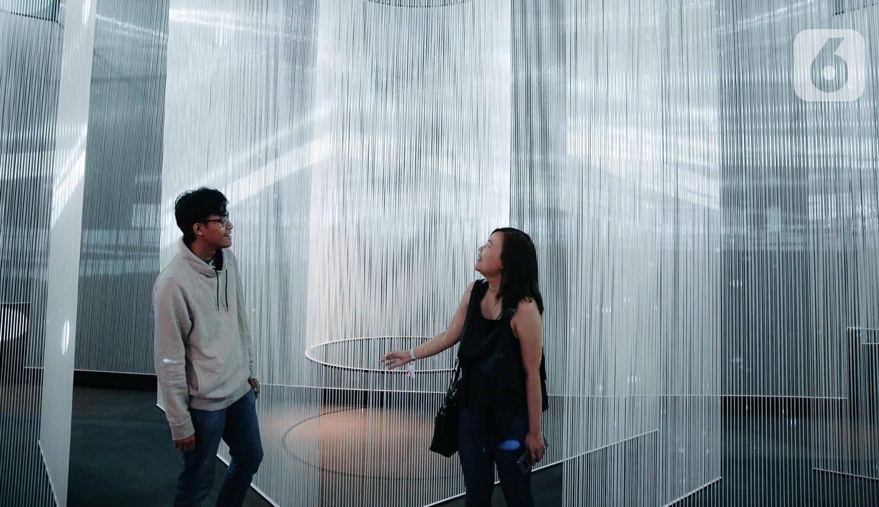 Pengunjung berpose saat mengunjungi pameran seni berbasis teknologi berwujud sorotan cahaya futuristik 'Wave of Tomorrow' di Jakarta, Sabtu (21/12/2019). Pameran seni Wave of Tomorrow menghadirkan tiga kelompok instalasi yaitu legacy, now, dan tomorrow.  (Liputan6.com/Faizal Fanani)