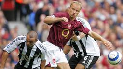 Striker Arsenal, Dennis Bergkamp (tengah) berebut bola dengan bek Newcastle United, Stephen Carr pada laga Liga Inggris 2005/2006 di Highbury Stadium, London (14/8/2005). Dennis Bergkamp didatangkan Arsenal dari Inter Milan pada awal musim 1995/1996. The Gunners harus mengeluarkan mahar sebesar 11,25 juta euro. Bertahan selama 11 musim di Arsenal hingga pensiun pada Juli 2006, ia total bermain dalam 417 laga dengan torehan 119 gol dan 98 assist. (AFP/Odd Andersen)