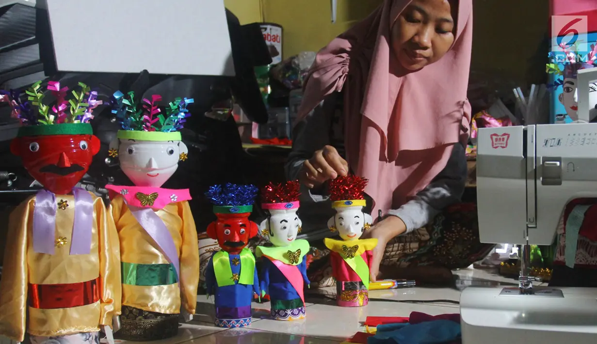 Perajin menyelesaikan pembuatan miniatur ondel-ondel di rumah produksi Kramat Jati, Jakarta, Senin (23/6/2019). Miniatur ondel-ondel yang terbuat dari limbah botol plastik itu dibuat sesuai dengan pesanan. (merdeka.com/Arie Basuki)