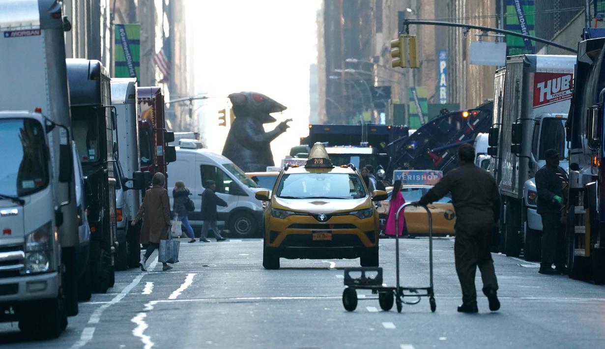 Balon tikus raksasa berjalan di tengah kota untuk diletakkan di luar kantor perusahaan sebagai simbol protes di New York, Kamis (26/12/2019). Serikat pekerja Amerika telah menggunakan balon tikus  untuk menyoroti praktik perburuhan yang tidak adil sejak 1990-an. (TIMOTHY A. CLARY/AFP)