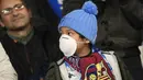 Seorang anak mengenakan masker menunggu dimulainya pertandingan antara Napoli dan Barcelona di Stadion San Paolo di Naples, Italia, Selasa, (25/2/2020). Sedikitnya tujuh pasien virus corona di Italia dilaporkan meninggal dunia. (AFP Photo/Filippo Monteforte)