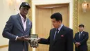 Mantan pemain Chicago Bulls, Dennis Rodman memberikan sebuah buku berjudul "Trump The Art Of The Deal" kepada menteri olahraga Korea Utara Kim Il Guk di Pyongyang, Korea Utara (15/6). (AP Photo/Kim Kwang Hyon)