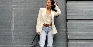 Acha Septriasa mengenakan blazer putih dengan padu padan kasual. Sebagai innerwear, Acha Septriasa tampak memilih lingerie putih, yang dipadunya dengan celana jeans. Ia juga menambahkan beberapa detail aksesori sebagai pemanis, seperti belt cokelat dan shoulder bag hitam. Foto: Instagram.