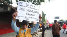 Warga menunjukkan poster bertuliskan selamat untuk pernikahan putri Presiden Jokowi,  Kahiyang Ayu dan Bobby Nasution saat menyaksikan prosesi kirab kereta kencana menuju Gedung Graha Saba di Surakarta, Rabu (8/11). (Liputan6.com/Angga Yuniar)