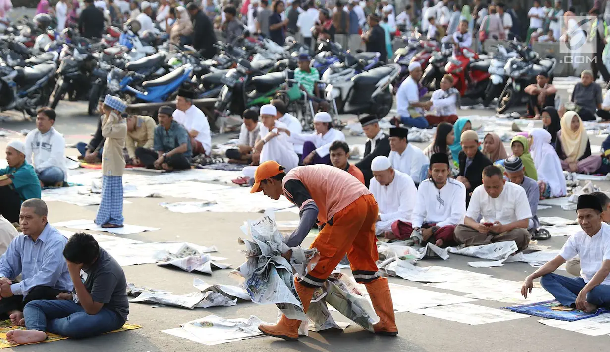 Petugas kebersihan memungut koran usai salat id Hari Raya Idul Fitri 1 Syawal 1439 H di kawasan Senen, Jakarta, Jumat (15/6). Banyaknya koran berserakan membuat petugas harus sigap membersihkan agar tidak mengotori jalan. (Liputan6.com/Immanuel Antonius)