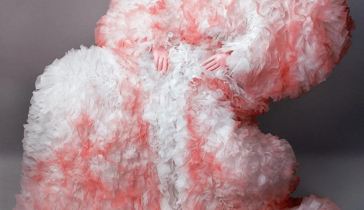 Tubuh Lady Gaga dibalut atasan dan trouser berbulu dari Tomo Koizumi. Gradasi warna merah dan putih membuat headpiece dari Alexander McQueen yang dikenakan Lady Gaga nampak mencolok.