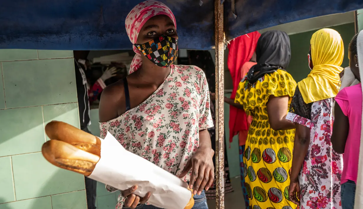 Ndyeye Fatou, putri Bara Tambedou, mengenakan masker saat membeli roti pada bulan suci Ramadan, di Dakar, Senegal, 25 April 2020. Tahun ini, banyak keluarga menjalankan Ramadan di rumah dengan larangan pertemuan publik dan jam malam untuk menekan penyebaran Covid-19. (AP/Sylvain Cherkaoui)