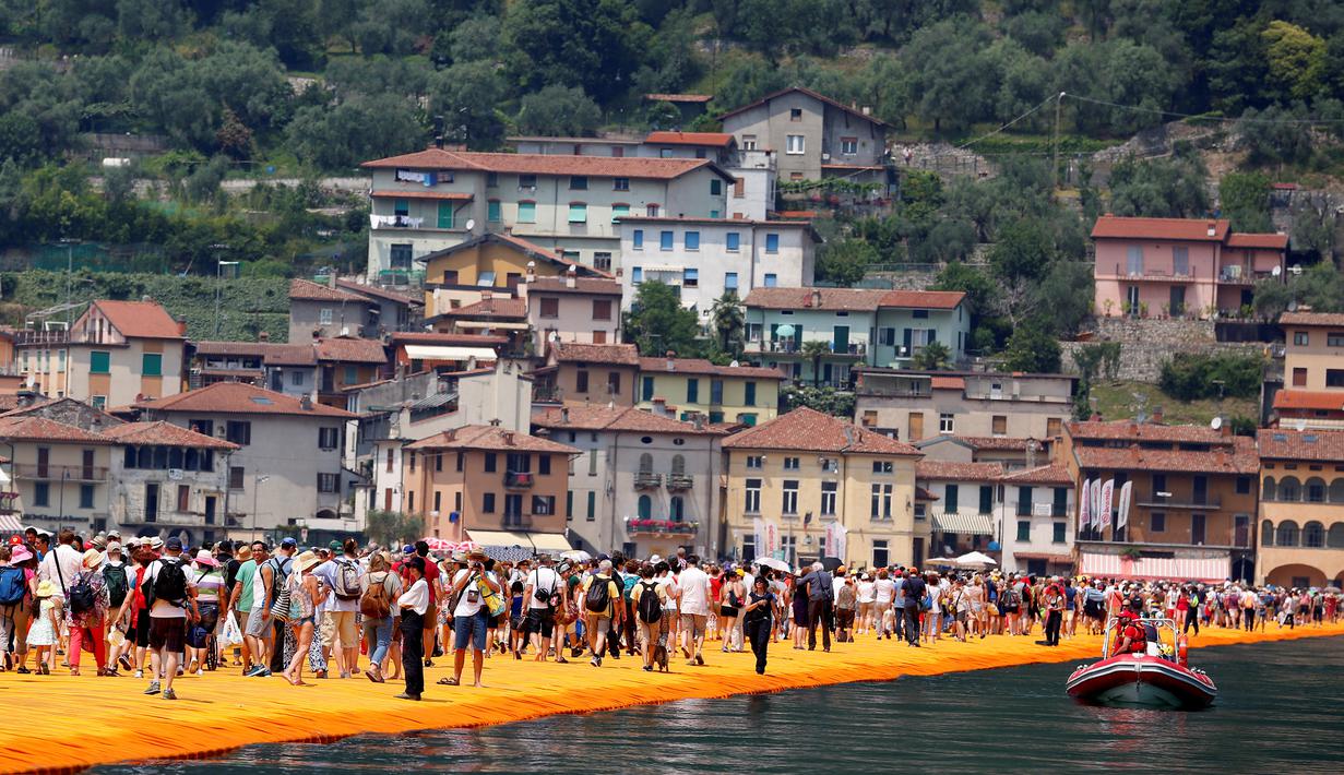 Sejumlah wisatawan berjalan di atas instalasi "The Floating Piers" karya Christo Vladimirov Javacheff di Danau Iseo, Italia, (24/6). Proyek seni instalasi ini telah menghabiskan biaya USD 16,7 juta atau sekitar Rp 224 miliar. (REUTERS/Stefano Rellandini)