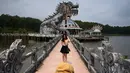 Foto pada 27 April 2019 memperlihatkan pengunjung berpose di depan bangunan berbentuk naga di Taman Air Ho Thuy Tien yang telah lama ditinggalkan di kota Hue, Vietnam. Taman air Ho Thuy Tien pertama kali dibuka untuk umum dalam keadaan setengah selesai pada tahun 2004. (Manan VATSYAYANA/AFP)