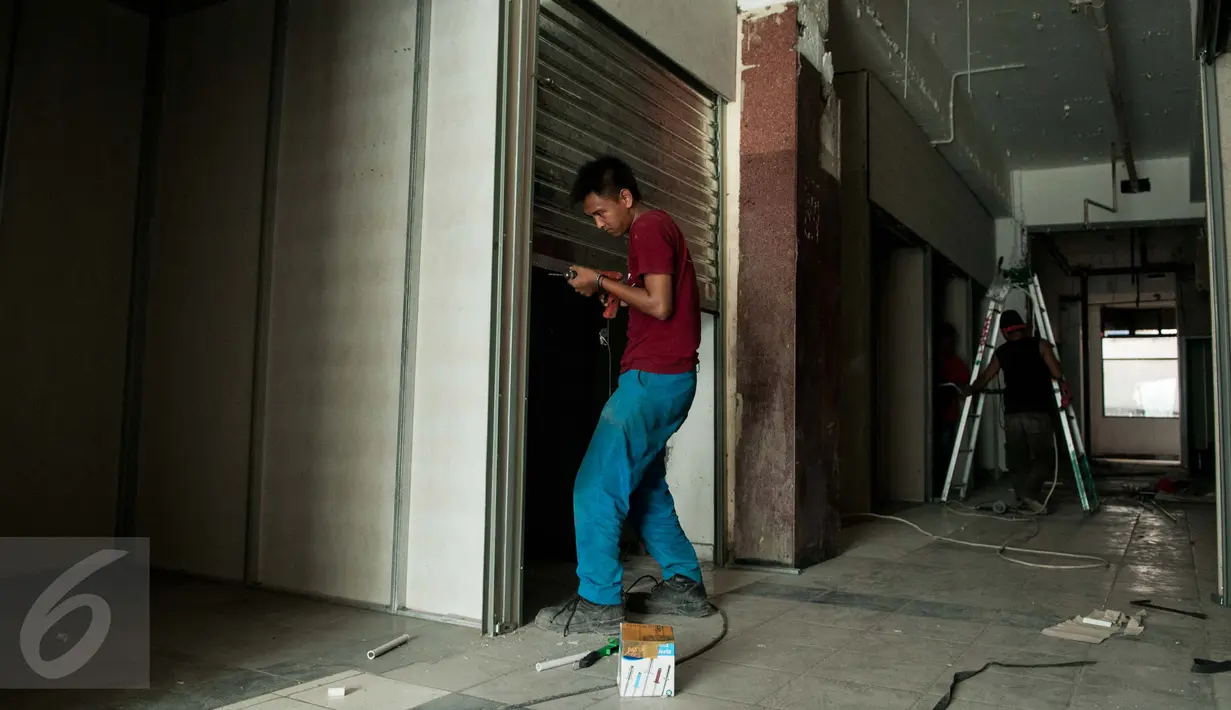Pekerja menyelesaikan pemasangan rolling door kios penampungan sementara bagi pedagang korban kebakaran di lantai 1 Blok V Pasar Senen, Jakarta, Jumat (24/2). Penampungan sementara itu dijadwalkan rampung pada Maret 2017. (Liputan6.com/Gempur M Surya)