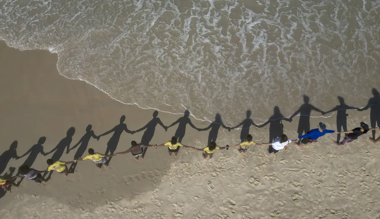 Orang-orang membuat barisan berpegangan tangan di sepanjang pantai Sao Conrado untuk berpelukan secara simbolis dengan laut pada Hari Laut Sedunia di Rio de Janeiro, Brasil, Kamis, 8 Juni 2023. (AP Photo/Bruna Prado)