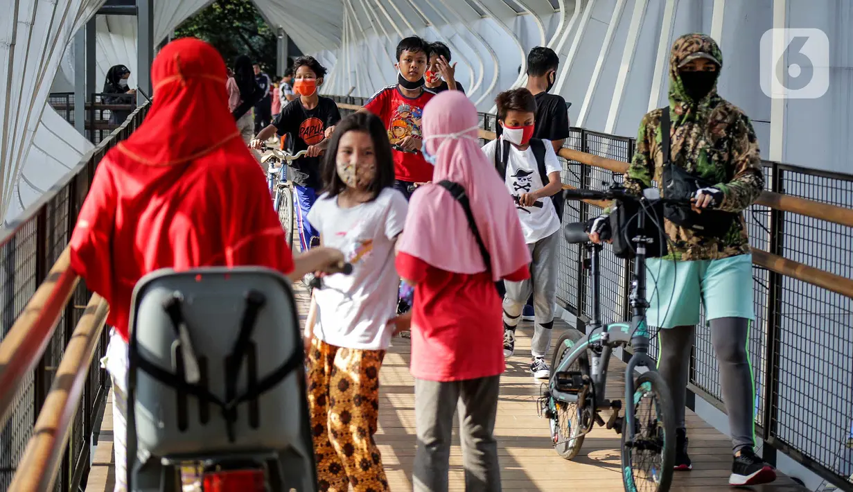 Warga melewati jembatan penyeberangan orang saat berolahraga menggunakan sepeda di sepanjang Jalan Sudirman, Jakarta, Minggu (26/7/2020). Pemprov DKI menyiapkan 30 kawasan khusus pesepeda di lima kota administrasi Jakarta. (Liputan6.com/Faizal Fanani)