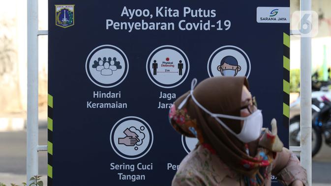 Warga di depan papan himbauan pencegahan penyebaran Covid-19 di area pedestrian Stasiun Terpadu Tanah Abang, Jakarta, Kamis (27/8/2020). Guna menekan penyebaran Covid-19, Polda Metro Jaya dan Kodam Jaya terus mengampanyekan pentingnya menaati protokol kesehatan. (Liputan6.com/Helmi Fithriansyah)