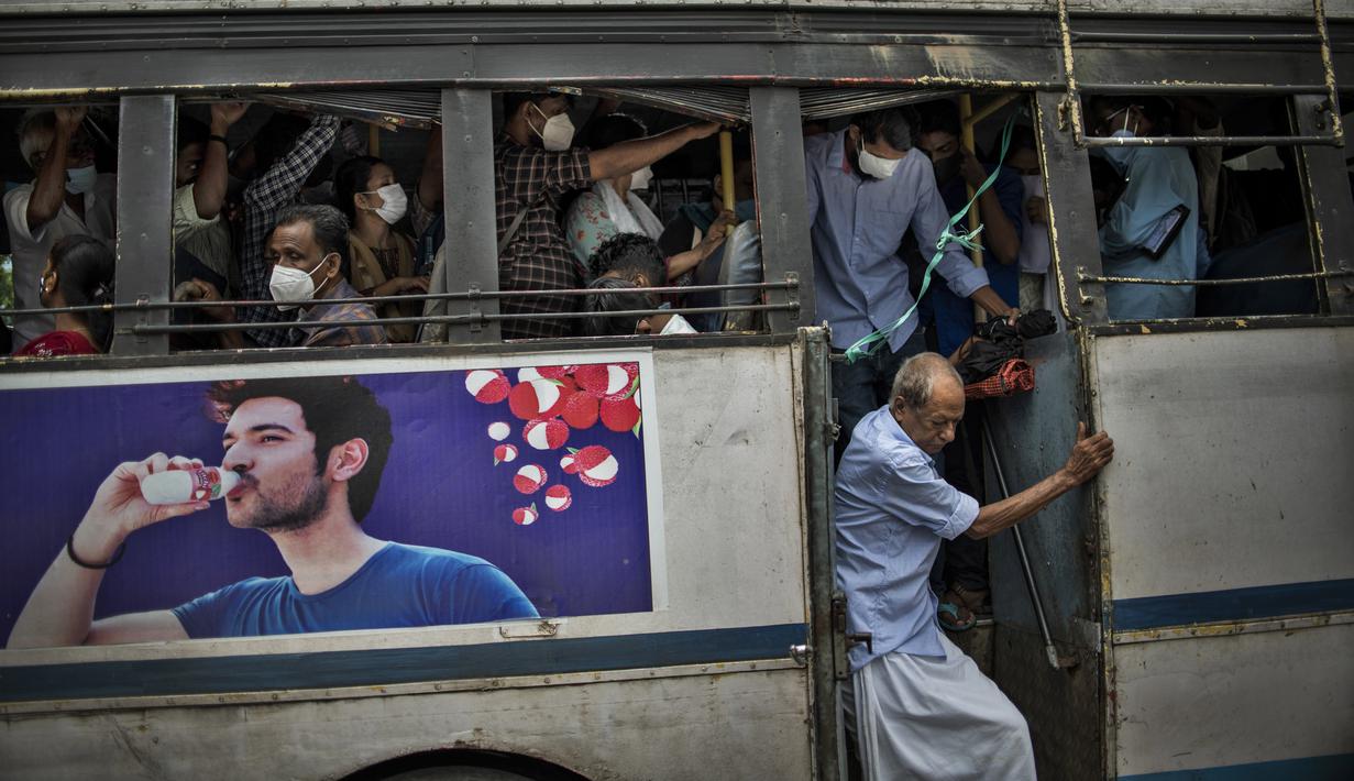 Seorang pria tanpa masker turun dari bus yang penuh sesak di Kochi, negara bagian Kerala, India, Rabu (6/7/2022). Negara bagian selatan itu telah mewajibkan penggunaan masker di tempat-tempat umum menyusul meningkatnya kasus COVID-19. (AP Photo/ RS Iyer)