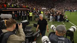 Pelatih AS Roma, Jose Mourinho memegang medali dan berjalan menuju ruang ganti setelah timnya dikalahkan Sevilla lewat babak adu penalti dalam partai final Liga Europa 2022/2023 yang berlangsung di Stadion Puskas Arena, Hungaria, Jumat (01/06/2023) dini hari WIB. (AFP/Odd Andersen)