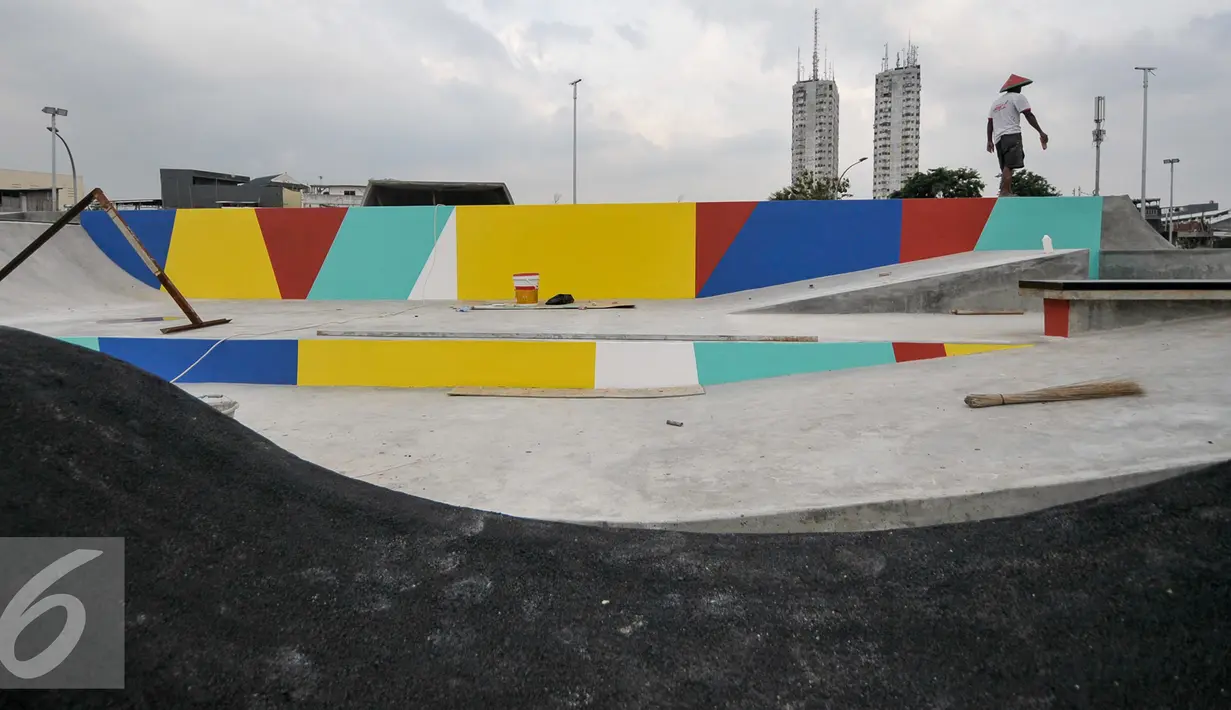 Seorang pekerja mengecat tembok bagian skate park yang masih dalam tahap pembangunan di kawasan Kalijodo, Tambora, Jakarta Barat, Selasa (6/12). Agar nantinya membantu mengembangkan bakat pemuda dan atlet skateboard Indonesia. (Liputan6.com/Yoppy Renato)