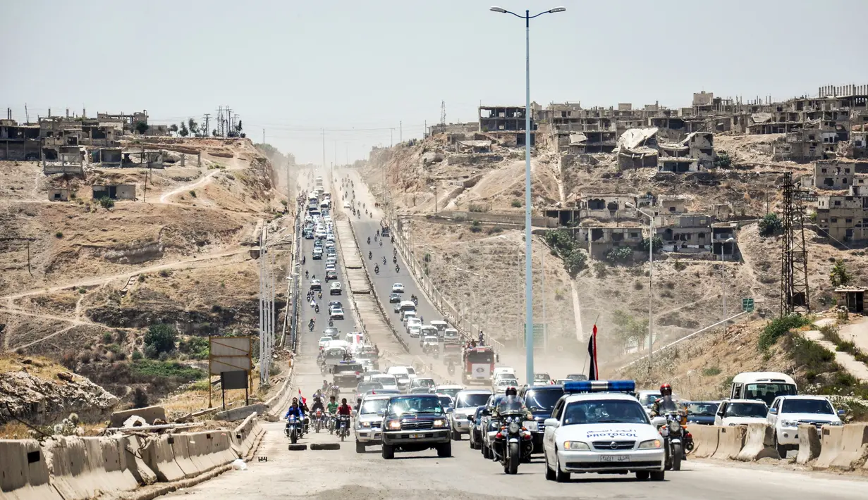 Mobil-mobil pemerintah dan kendaraan militer melintasi jalan raya utama antara Homs dan Hama di Suriah tengah, Rabu (6/6). Pemerintah Suriah membuka kembali jalan raya Homs-Hama setelah ditutup selama hampir tujuh tahun. (AFP/STRINGER)