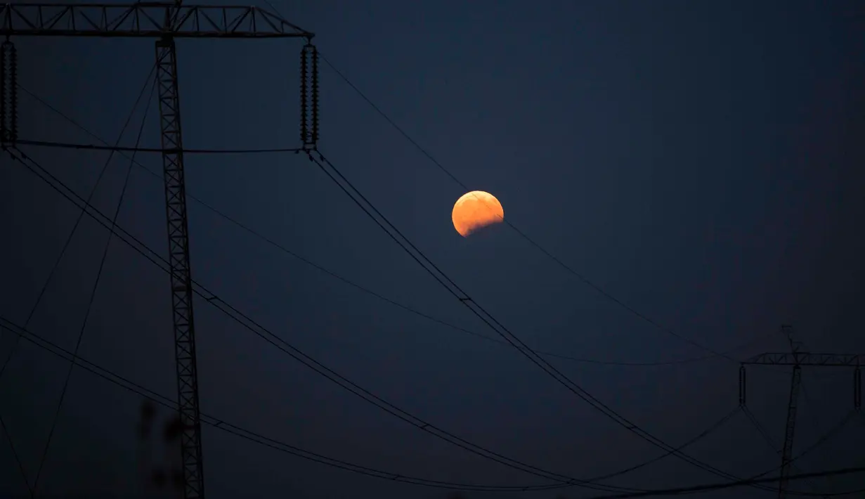 Gerhana bulan parsial terlihat di balik jalur transmisi tenaga listrik di Kosovo, Senin (7/8). Gerhana bulan parsial bisa dilihat di seluruh Indonesia, sebagian benua Eropa, sebagian Afrika, Australia dan seluruh negara benua Asia (AP Photo/Visar Kryeziu)