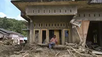 Permukiman warga nyaris hilang dan hancur, rata dengan lumpur. Tampak dalam foto, seorang warga duduk di depan rumahnya yang rusak akibat banjir bandang di Garoga, Provinsi Sumatera Utara, pada Kamis 4 Desember 2025. (YT HARIONO/AFP)