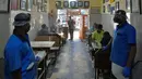 Pramusaji mengenakan pelindung wajah dan masker di sebuah restoran yang dibuka kembali usai pelonggaran lockdown di Bangalore, India, Senin (8/6/2020). Untuk keamanan pelanggan, restoran-restoran menyiapkan panel transparan di meja makan sebagai pencegahan COVID-19. (Manjunath Kiran/AFP)