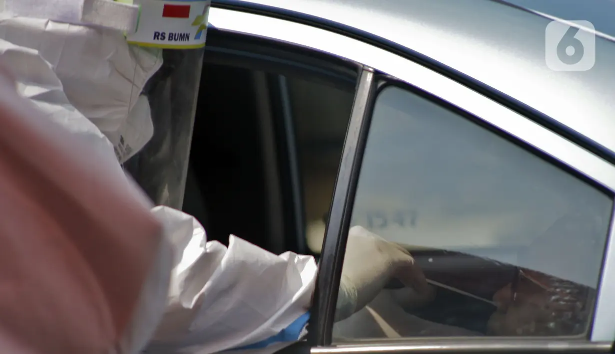 Petugas berpakaian APD lengkap melayani pasien yang secara mandiri melakukan swab test drive thru di halaman parkir rumah sakit di Jakarta, Rabu (12/5/2020). Swab test drive thru dilakukan untuk mendeteksi dan mencegah penyebaran virus corona COVID-19. (Liputan6.com/Johan Tallo)