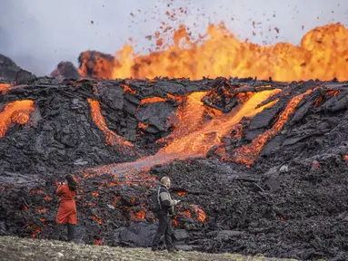 Orang-orang melihat lava yang mengalir di gunung berapi Fagradalsfjall di Islandia pada Rabu (3/8/2022), yang terletak 32 kilometer (20 mil) barat daya ibu kota Reykjavik dan dekat dengan Bandara Internasional Keflavik. Pihak berwenang di Islandia mengatakan gunung berapi di barat daya negara itu meletus hanya delapan bulan setelah letusan terakhirnya secara resmi berakhir. (AP Photo/Marco Di Marco)