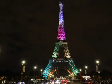Pengunjung berjalan di sekitar Menara Eiffel yang diterangi dengan huruf bertuliskan '300 juta terima kasih' di Paris, Kamis (28/9). Menara Eiffel pada Kamis waktu setempat merayakan pengunjung ke-300 jutanya sejak dibuka pada 1889. (LUDOVIC MARIN/AFP)