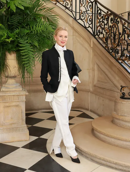 Naomi Watts tampil necis dengan kemeja putih berkerah tinggi dan celana pendek. Setelan ini dilapisi blazer hitam berkancing mutiara [Dior]