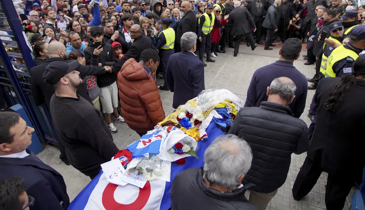 Para fans sepak bola nan mengenakan jersey klub-klub Uruguay memberikan penghormatan mereka kepada Juan Izquierdo. (Dante Fernandez / AFP)